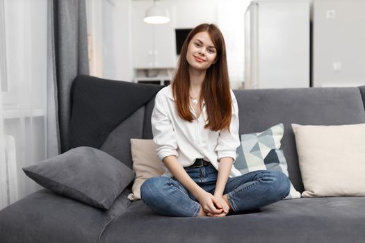 woman sitting on the couch bending her knees at home in an apartment rest