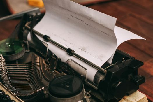 vintage typewriter with keys on a wooden background and a white sheet of paper