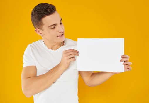 young man with white sheet of paper on yellow background cropped view Copy Space. High quality photo
