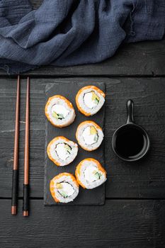 Sushi roll, Philadelphia with salmon, smoked eel, avocado, cream cheese, on black wooden table background, top view flat lay
