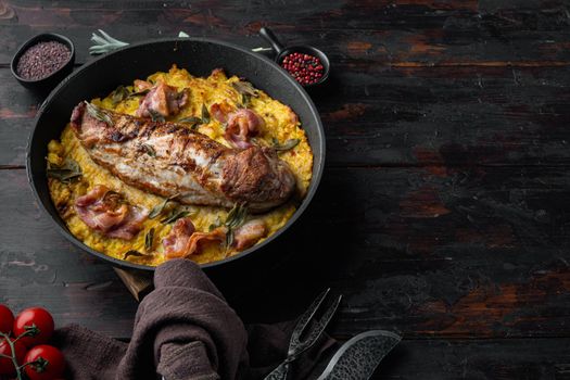 Grilled pork fillet and mash potatoe gratin with sage and prosciutto , on frying cast iron pan , with barbeque knife and meat fork, on old dark wooden table background , with copyspace and space for text