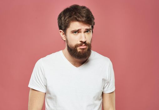 Man with a brunet beard pink background white t-shirt emotions