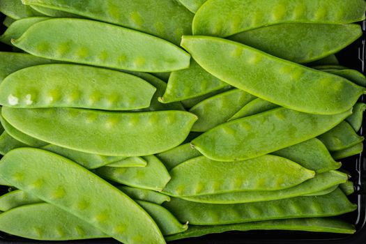 Healthy snap peas, on black stone background, top view flat lay