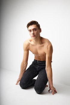 Man kneeling in black trousers nude torso posing lifestyle