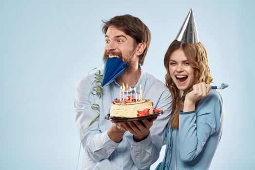 Young couple birthday celebration cake fun blue background. High quality photo