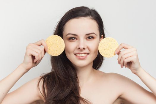 woman with bare shoulders loose hair clean skin sponges in hands