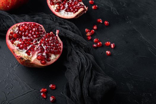 Ripe pomegranate with fresh juicy seeds, on black textured background with space for text