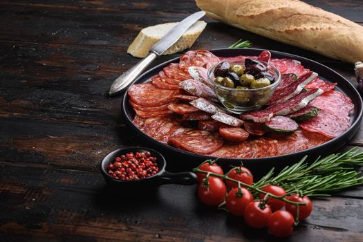 Antipasto platter cold meat with chorizo, fuet,salami, salchichon and longaniza on dark wooden background with space for text