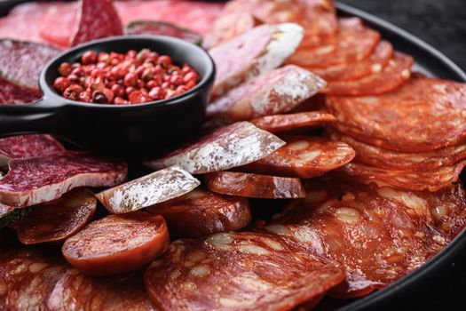 Antipasto platter cold meat with chorizo, fuet,salami, salchichon and longaniza on black textured background