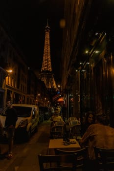 Beautiful lighted Eiffel Tower from a crowded street at night