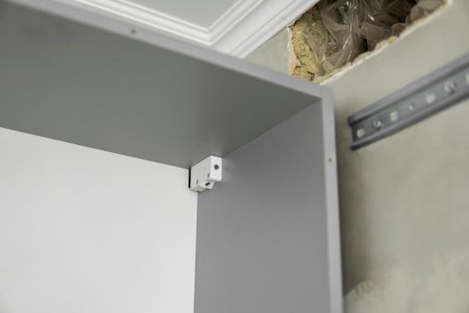 Hardware kitchen cabinet suspension brackets on a custom kitchen from a chipboard material. Cabinet hanger.