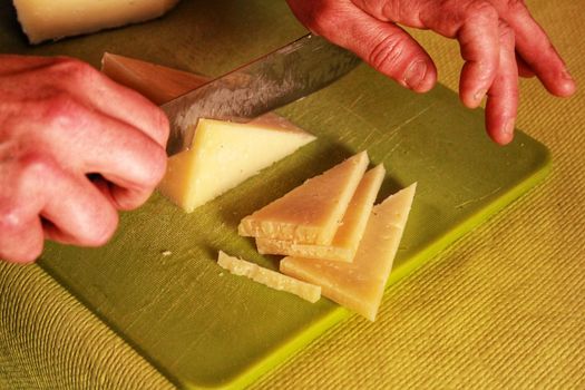 Hands slicing Manchego cheese slices in triangles