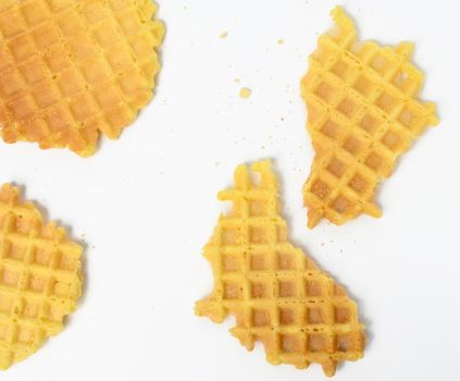 baked round belgian waffles on white background, broken pieces and crumbs