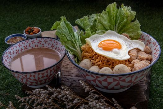 Egg noodle with pork ball, minced pork, fried egg, vegetables and soups in bowl. 