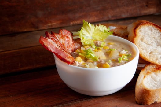 Corn chowder soup with bacon. Brown wooden background. Close-up view