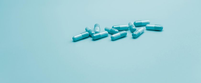 Blue antibiotic capsule pills on pastel blue background. Pharmacy web banner. Antibiotic drug resistance. Antimicrobial capsule pills with space. Health budget and policy. Pharmaceutical industry. 