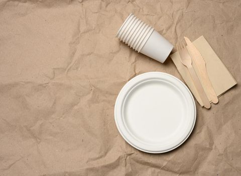 disposable round white paper plates and cups on brown paper background