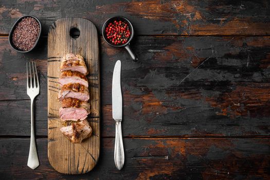 Delicious sliced roast duck breast, on wooden serving board, on old dark wooden table background, top view flat lay, with copyspace and space for text