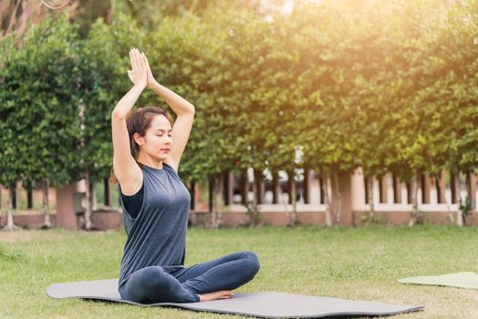 woman practicing yoga outdoors in meditate pose sitting on green grass