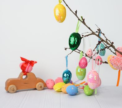 wooden toy car carrying a pink Easter egg fixed with a red ribbon