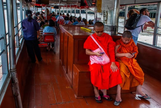 The monks and novices are watching mobile messages during the Chao Phraya Express Boat Ride.