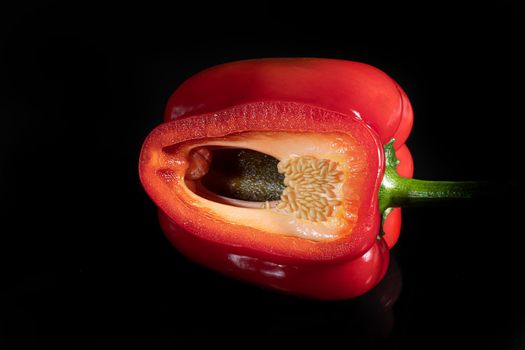 Red bell pepper in a cut on a black background. Isolate. Foreground.