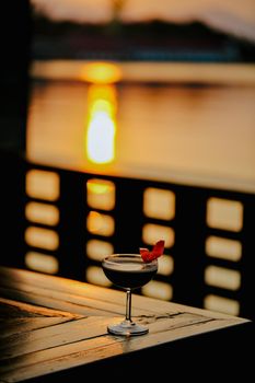 dark cocktail garnished with an orange twist on a dark bar setting.