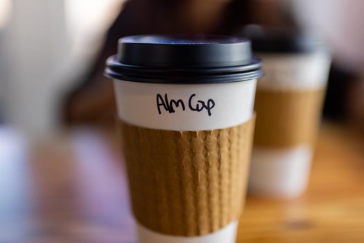 White and brown disposable paper coffee cup with blurry background