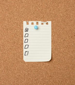 blank sheet of paper in a line attached with a plastic button on a brown cork board