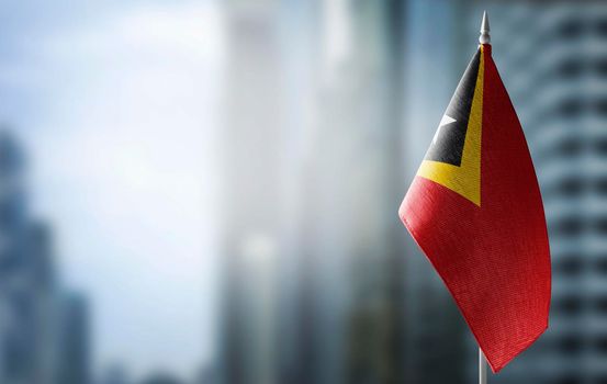 A small flag of East Timor on the background of a blurred background