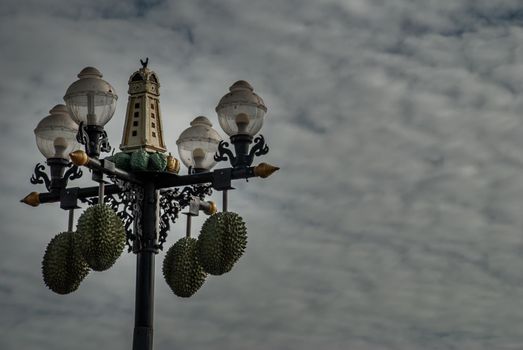 Street lamp in front of the Chinese shrine decorated with durian balls and has a background of blue sky and white clouds. Space for messages.