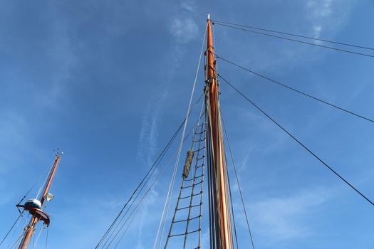 Sailing ship mast against the blue sky on some sailing boats with rigging details.