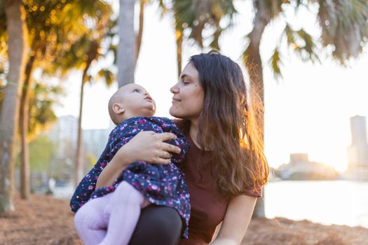 Beautiful view of woman holding a baby with bright sunset as background