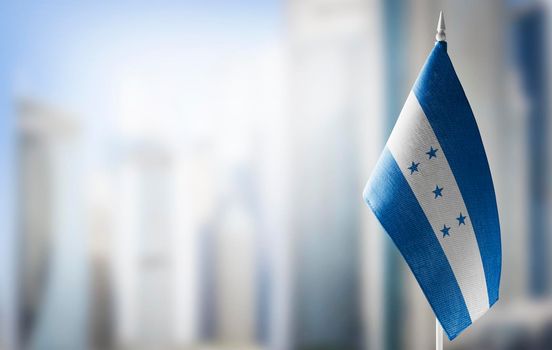 A small flag of Honduras on the background of a blurred background