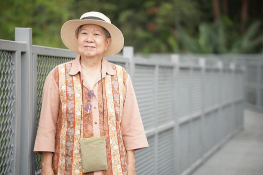 old elderly female elder woman traveller traveling on footbridge in park. senior lifestyle