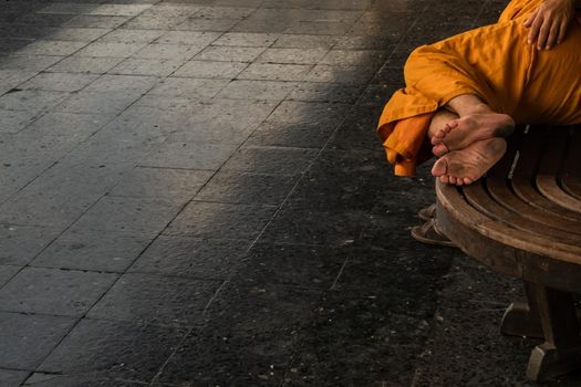 A monk is sleep on wooden chairs are waiting for trains in the area provided at Main railway station of Hua Lamphong.