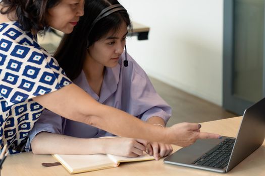 Asian mother with computer notebook teaching daughter to learn or study online at home, Homeschooling online concept.