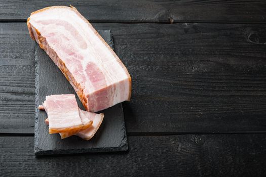 Smoked bacon, whole slab on black wooden table with space for text
