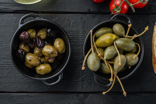 Mediterranean olives and capers, on black wooden table, flat lay