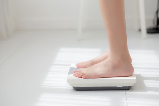 Lifestyle activity with leg of woman stand measuring weight scale for diet with barefoot, closeup foot of girl slim weight loss measure for food control and nutrition, healthy care and wellness concept.