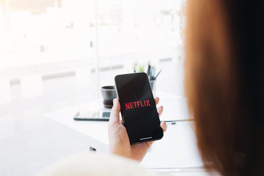 CHIANG MAI, THAILAND, MAR 12 2020: Woman hand holding Smart Phone with Netflix logo on Apple iPhone Xs. Netflix is a global provider of streaming movies and TV series.