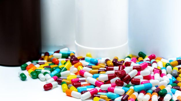 Pile of colorful antibiotic capsule pills on blur plastic drug bottle. Antibiotic drug resistance. Antibiotic drug overuse. Pharmaceutical industry. Polypharmacy. Antimicrobial drugs. Bright pills.