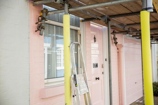 Scaffold outside the window and door of a pink British house