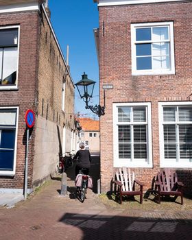 woman rides bicycle on old street in dutch town of zierikzee in spring