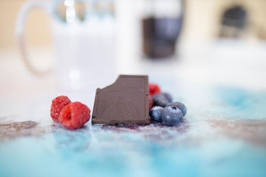 Bitten chocolate bar and berries on a colorful placemat