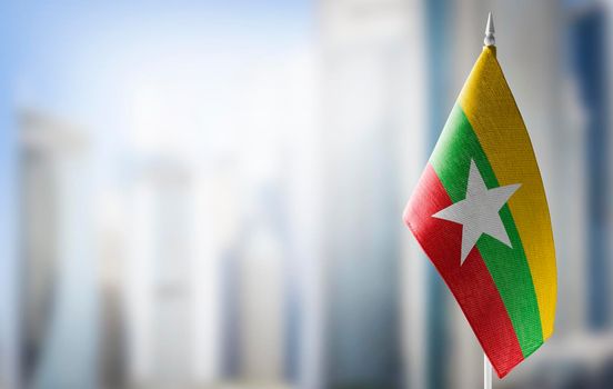 A small flag of Myanmar on the background of a blurred background