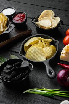 Variation different potato chips, on black wooden background