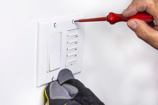 Electrician tightens the screws that secure the switch cover