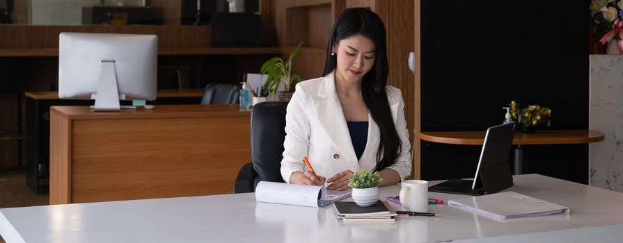 Business woman reading minute of meeting on her notebook in office.