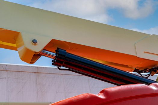 Closeup hydraulic of boom lift. Orange articulated boom lift. Maintenance and repair hydraulic boom lift service. Aerial platform. Telescopic boom lift. Mobile construction crane. Hydraulic cylinder.